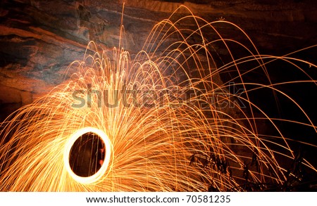 Burning Steel Wool. image of steel wool on fire while spinning in the outdoors by a large rock