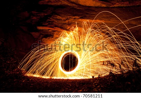 Burning Steel Wool. image of steel wool on fire while spinning in the outdoors by a large rock
