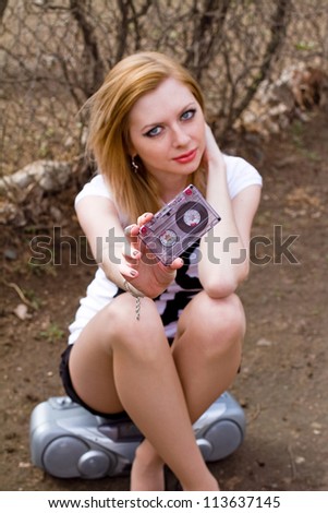 Beautiful girl with cassette and tape recorder near the fence