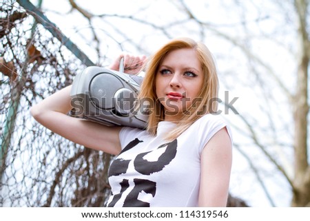 Beautiful girl with tape recorder shoulder near the fence