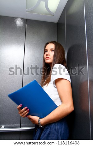 Young business woman with a folder in a lift