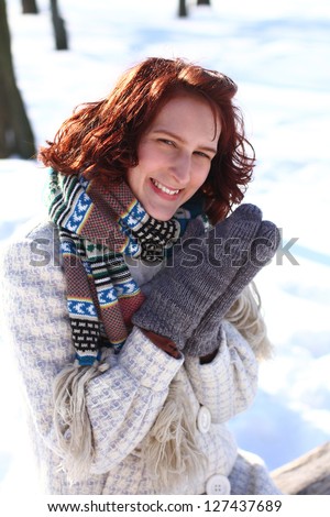 Sweet smiling young woman in a winter park sitting