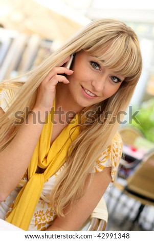 beautiful young blond woman in a cafe with a cell phone
