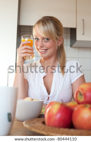 young blond woman with a glass of juice/young blond woman with a glass of juice in a kitchen