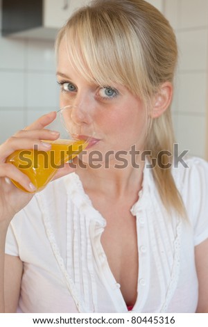 young blond woman drinks juice out of a glass/young blond woman drinks juice out of a glass