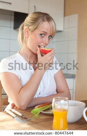 young blond woman bites off from an apple/young blond woman bites off from an apple at the breakfast table