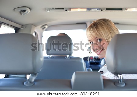 young blond woman on a backseat of a car/young blond woman on a backseat of a car smiles