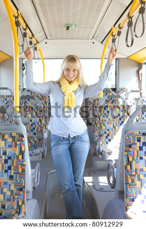 young blond woman inside a bus holds on tight to handles/young blond woman inside a bus holds on tight to handles