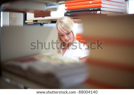 young blond woman in a library with a big book/blond woman with a big book