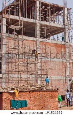DELHI, INDIA - MARCH 28, 2014:  Workers on scaffolding at the side of a building under construction in the Indian capital