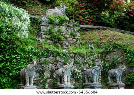 The part of Indian style presentation in Scherrer Park in Morcote, elefant, cobras and caw sculptures are integrated in the stone wall decorated with plants and flowers.