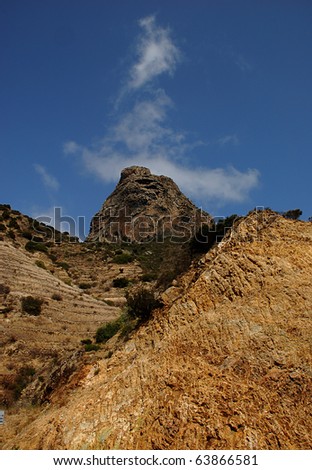 We can see a high roc, on a mountain of roc also with some herbs on it. And in the background the is the sky with little clouds. This scene takes place in La Gomera, A Canarian Island, Spanish Islands