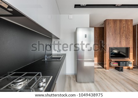 Kitchen with fridge, black worktop and backsplash, open to tv room