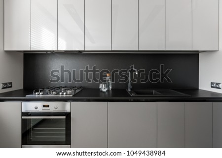 Modern kitchen unit in black and white, black worktop and backsplash
