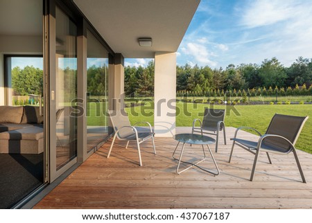 Stylish patio with wood flooring, and garden view, simple patio furniture set