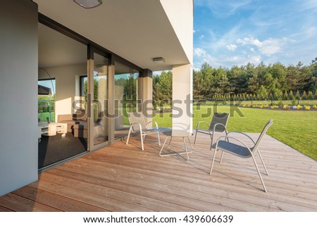 New outdoor furniture set standing on a modern patio, beautiful garden view