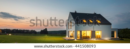 Panoramic photo of modern house with outdoor and indoor lighting, at night