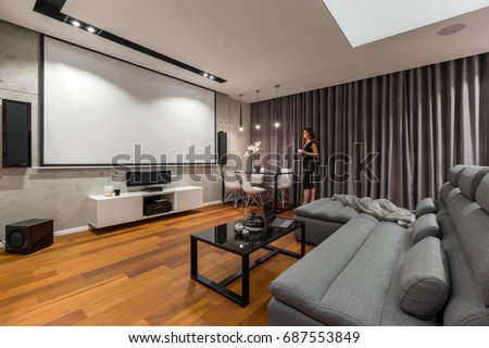 Woman in living room with projector screen, gray sofa and black coffee table