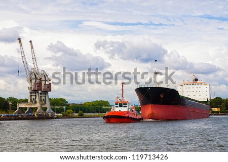 Tugboat towing a large ship in port Gdansk.