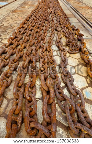 Steel anchor chains caked with rust at an shipyard.