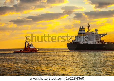 Tug boat pulling the tanker ship at sea.