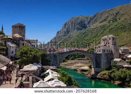 MOSTAR, BOSNIA AND HERZEGOVINA-JULY 20 : People walking on the street with many shops and cafes on July 20, 2014 in Mostar, Bosnia and Herzegovina. Old Bridge in background, UNESCO World Heritage Site