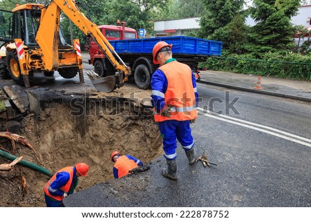 Workers repairing the damaged road - rupture of the pipeline