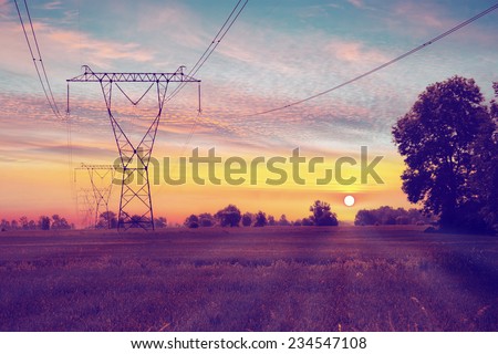 Electric towers on a field with sunrise.