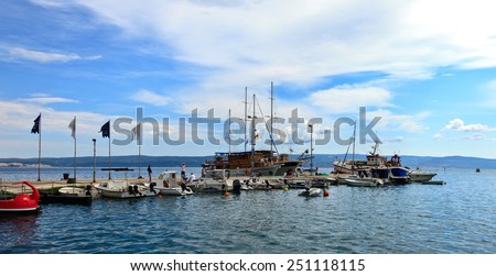 OMIS, CROATIA -  JULY 23: Tourists and locals walk the stone wharf against boats line the docks by the marina, on July 23, 2014 in Omis, Croatia. Omis a small tourist town in Dalmatia.