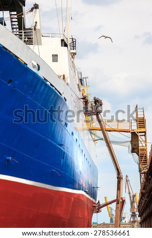 Shipyard worker to clean ship after painting.