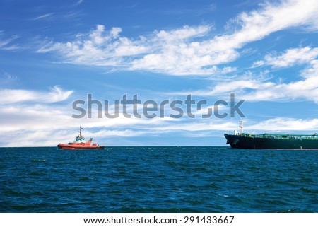 Tug boat towing a tanker ship at sea.