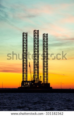 Oil drilling rig silhouette at sunset time.