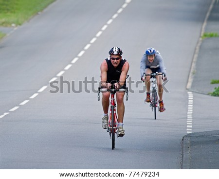 EAST GRINSTEAD, ENGLAND - MAY 15: Male competitor 391 Mark Royden cycles along road pursued by 420 Steven Delpy during the East Grinstead Triathlon on May 15 2011.