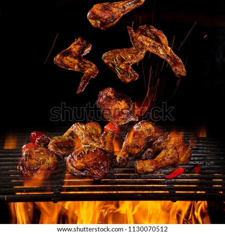 Tasty chicken legs and wings on the grill with fire flames