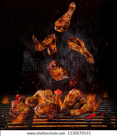 Tasty chicken legs and wings on the grill with fire flames