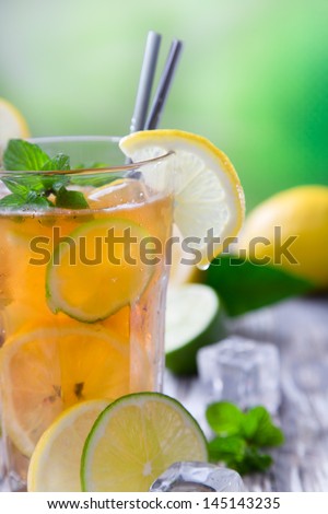 Glass of ice tea with ice-cubes on wooden table