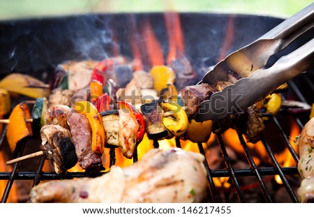Meat spits on grill flames in background