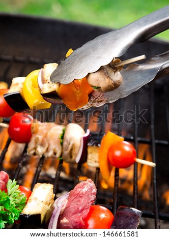 Meat spits on grill flames in background