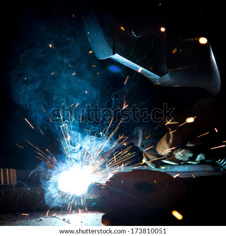 Welder in action with bright sparks. Construction and manufacturing theme.