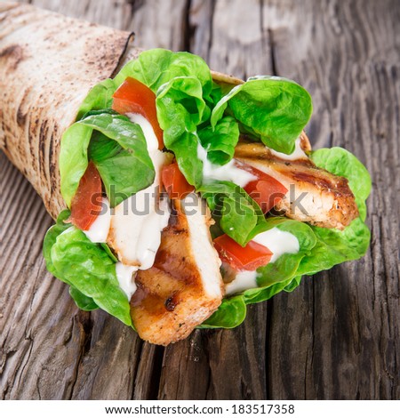 Chicken strips in a Tortilla Wrap with Lettuce on wood.