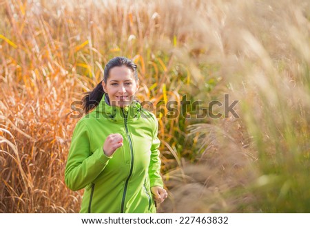 Young happy brunette woman training outside during autumn day and listening to music.