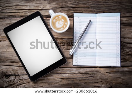 Workspace with coffee cup, tablet pc and note paper on old wooden table