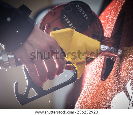 Hand refilling the car with fuel, close-up.