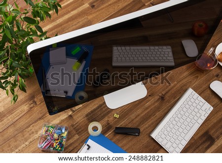 Workplace with computer, office supplies and wooden desk.