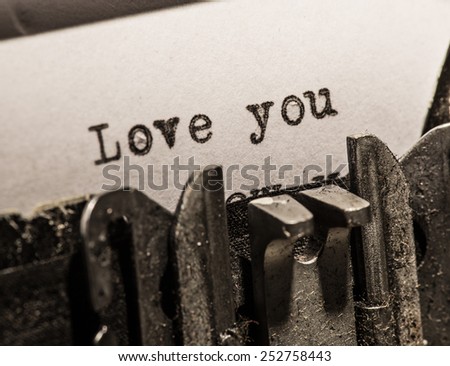 Typewriter with white paper page on wooden table. sample text Love you.