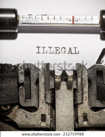 Typewriter with white paper page on wooden table. sample text Illegal.