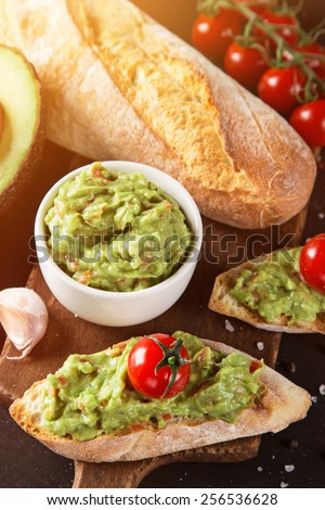 Guacamole with bread and avocado on stone background