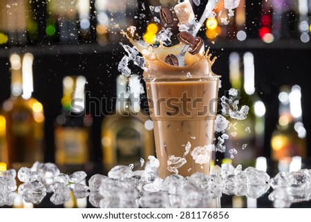 Cold coffee drink with ice, beans and splash, close-up.