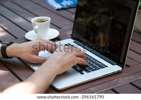 young man working from garden wooden table using notebook computer