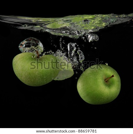 Fresh green apples splashing into the water